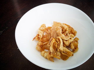 Close up of deep-fried chicken skins in a white bowl.
