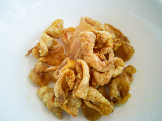 Close up of deep-fried chicken skins in a white bowl.