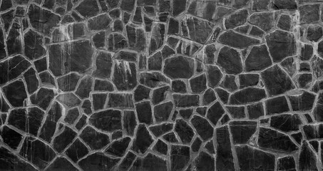 Obraz premium High resolution full frame background of an old, weathered and dirty stone wall with slates in black and white. Vignette and copy space.