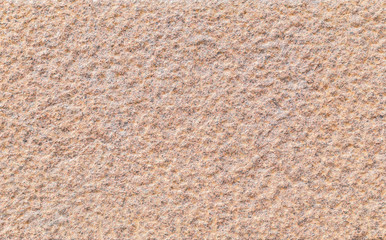 Close-up of a bumpy red granite stone wall. High resolution full frame background texture.