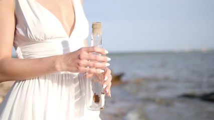 The girl puts her desire in the bottle and lets go into the sea. Bottle on the beach. More videos from this series in my portfolio