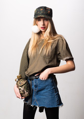 Magnificent white girl in military clothes posing with flask. Studio portrait of beautiful lady in jeans skirt looking on photographer.