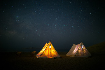 Camping under stars, night sky in the desert, the Milky Way, tents glowing from the inside....