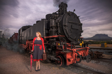 Fototapeta na wymiar Frau in Petticoat Kleid steht neben einen Dampflok