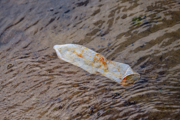 used condom left in water near shore on the beach