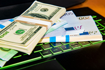 Money on a laptop, bundles of dollars and euros are on the keyboard of a laptop, the concept of online wages and the Internet win.