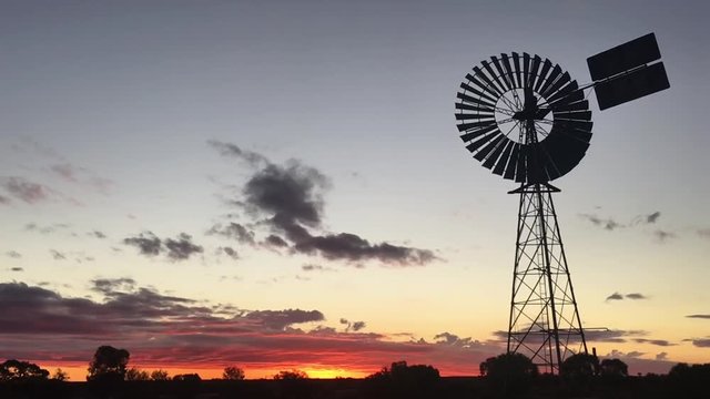 Silhouette of a large windmill in central Australia outback during dramatic sunset in slow motion