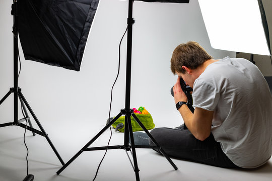junger Fotograf macht Stockfotos vor weißer Leinwand