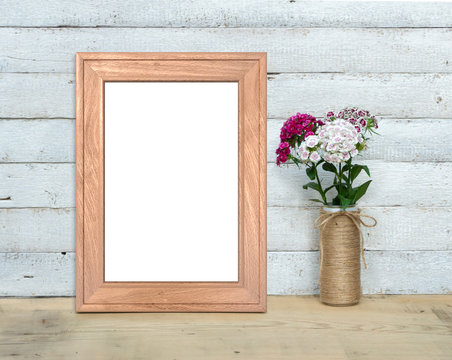 Old Wooden Frame mockup near a bouquet of sweet-william stands on a wooden table on a painted white wooden background. Vertical A4 Rustic style, simple beauty. 3d render. © photolas