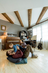 Happy young family playing on the floor at rustic room