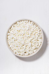 bowl of fresh farm cottage cheese on a white background, vertical top view