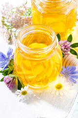 jars with fresh flower honey on white wooden board, vertical closeup