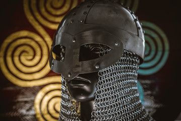 Soldier Viking helmet with chain mail of iron on red shield of wood and golden triskel