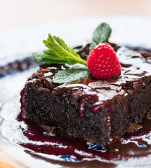 Chocolate cake with raspberry and mint leaf.