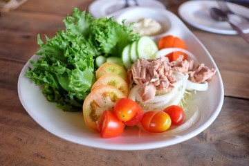 Close up Tuna salad with mixed fresh vegetables and mayonnaise sauce in a big plate on wooden dinning table at the restaurant