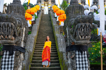 Bottom-up view of the Balinese temple decorated for the holiday Galungan. Woman standind on the stairs. Bali, Indonesia. Close up