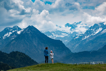 Naklejka premium Zwei Mädchen schauen auf die schneebedeckten Alpen