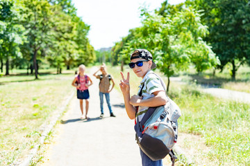 Stylish guy in a cap and sunglasses and a backpack with friends goes to study. Children go to school.