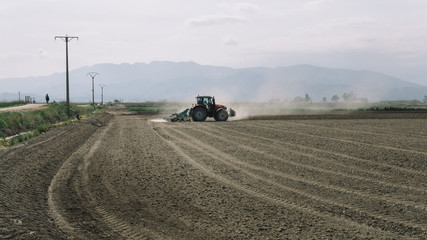 tractor plowing a dusty field