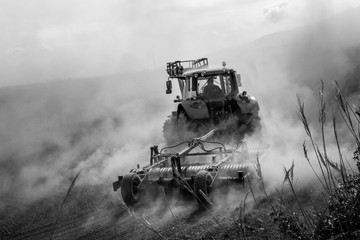 tractor plowing a dusty field