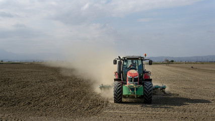 tractor plowing a dusty field
