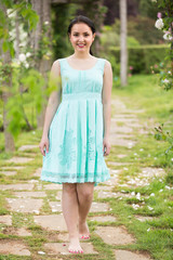 Fototapeta premium portrait of young female in dress near roses in a park