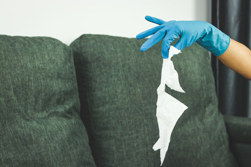 The housewife wears blue gloves to clean the house, hold used tissue paper.