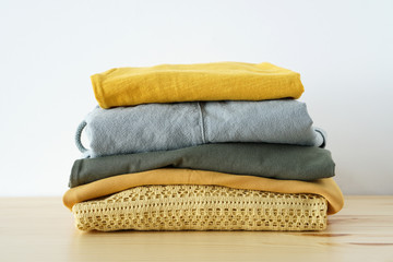 Stack of clothes in yellow green gamma on wooden table