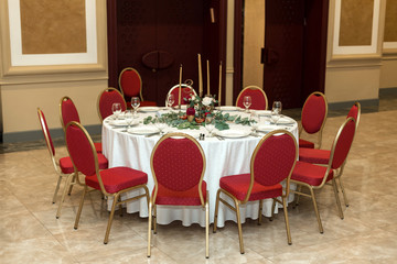 The wedding table setting is decorated with fresh flowers in a brass bowl and golden candles in brass candlesticks. Wedding floristry. Banquet table for guests. Bouquet with dahlias and eucalyptus