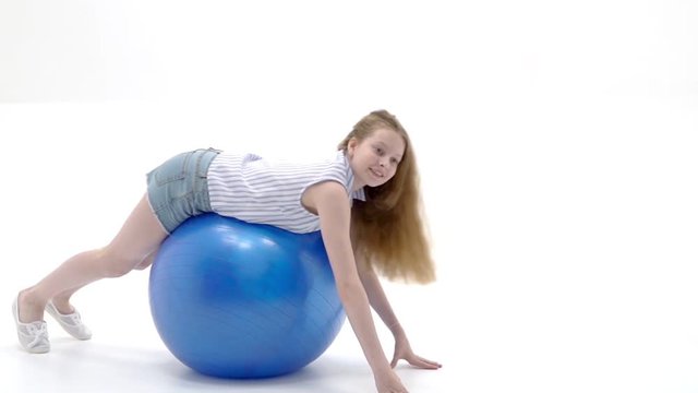 little girl doing exercises on a big ball for fitness.