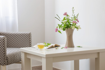 cup of tea, open book and summer  bouquet in vase indoor