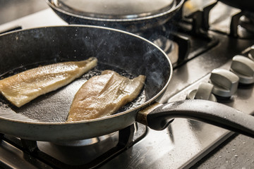 Fresh Fish on frying pan in kitchen, cooking concept.
