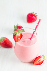 A glass of fresh strawberry smoothie on a wooden background. Summer drink shake, milkshake, juice and refreshment organic concept.