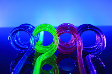 A color image of colored plastic straws on a blue reflective surface.
