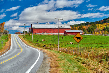 Highway and red barn at sunny autumn day in New Hampshire, USA