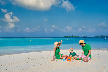 Fototapeta na wymiar Family on beach, young couple in green with three year old boy. Summer vacation at Maldives.