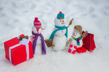 Greeting snowman family, parenthood concept. Cute snowmen family with - gift presents standing in winter Christmas landscape. Festive Art Greeting Card. Snowmen family - gift presents concept.