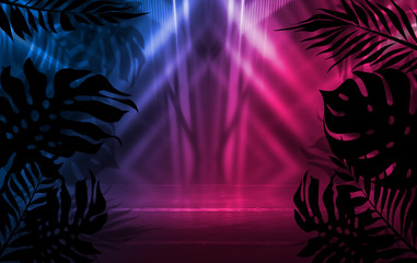 Background of empty dark scenes with neon lights and shapes, smoke. Silhouettes of tropical palm leaves in the foreground. Bright futuristic abstract background