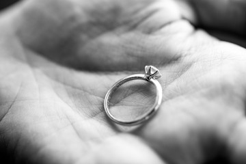 Woman hand holding wedding ring with diamond in monochrome