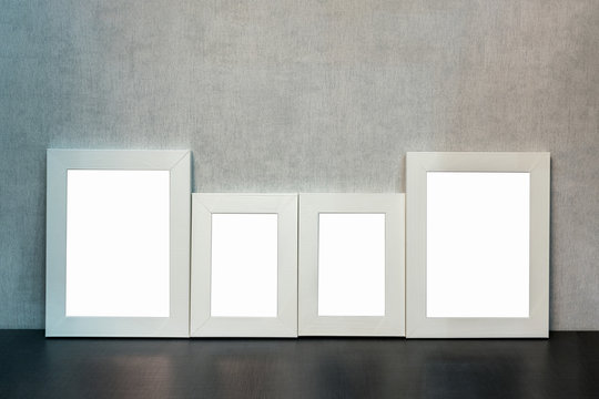 gallery of four blank photo frames or paintings on a shelf in the living room at home in the style of minimalism, mock-up