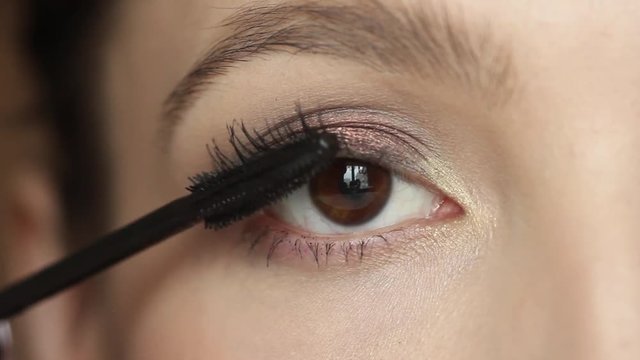 Closeup portrait of  woman applying mascara using  brush