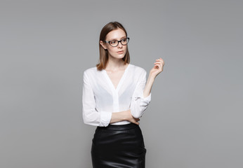 Portrait of the young modern business woman. The strict beautiful thin brunette with the equal business leader of the woman of hair in casual clothes. Gray background.