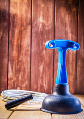 Clean plastic plunger with blue handle and cable on wooden background