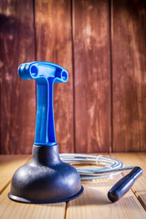 Clean plastic plunger with blue handle and cable on wooden background