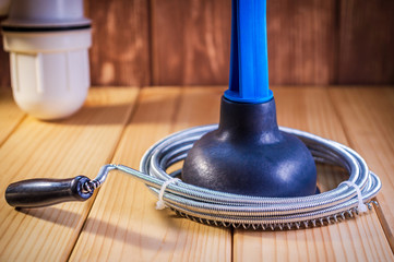 Clean plastic plunger with blue handle and cable on wooden background