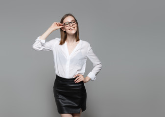 Portrait of young modern business woman. Smiling beautiful slim brunette with equal hair female business leader in casual wear expressing happy emotions. Gray background.