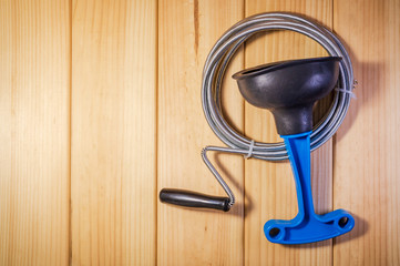 Clean plastic plunger with blue handle and cable on wooden background