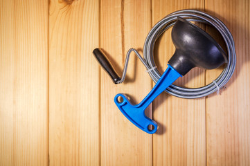 Clean plastic plunger with blue handle and cable on wooden background