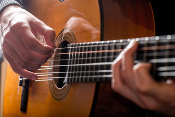 Fototapeta premium adult white guy playing an acoustic guitar. Backlit shooting