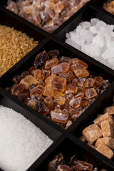 Various kinds of sugar in a wooden box. White refined, brown cane sugar collection